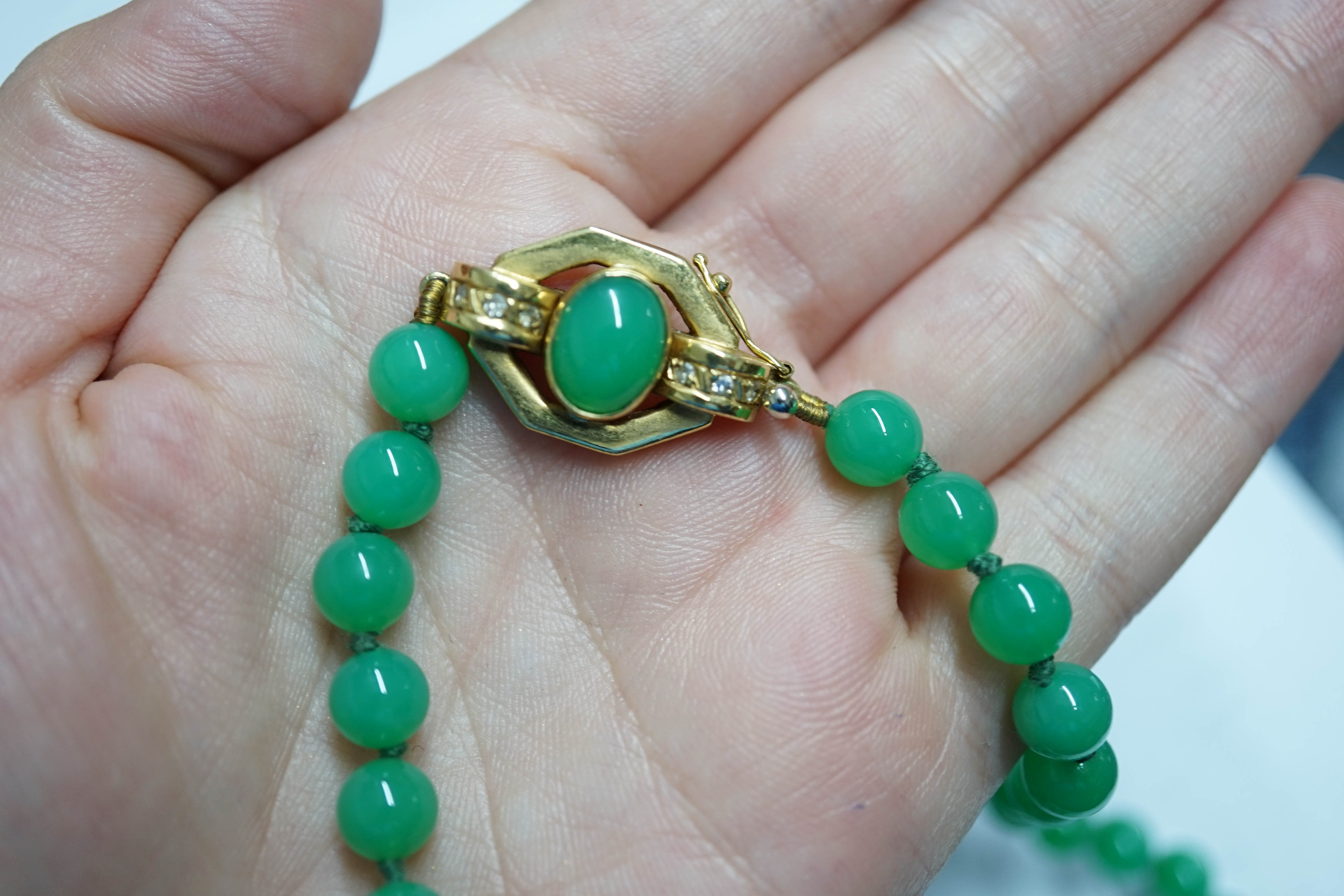 A modern long single strand jadeite bead necklace, with a cabochon jade and diamond chip cluster set 18k clasp